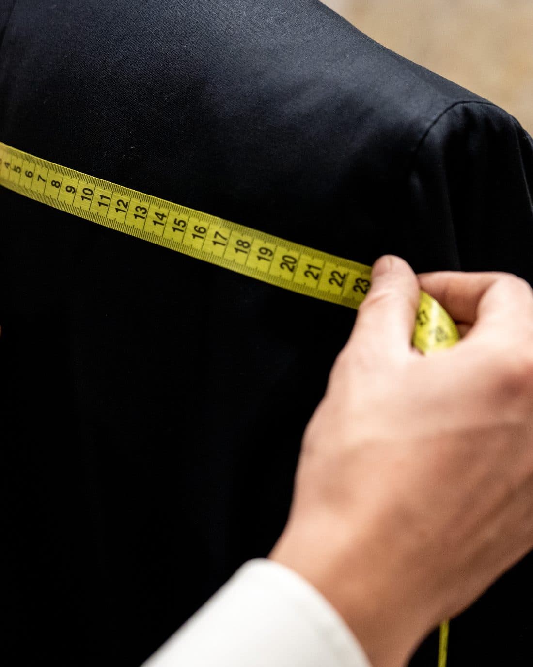 A tape measure held across the shoulder seam of a finished jacket during quality control