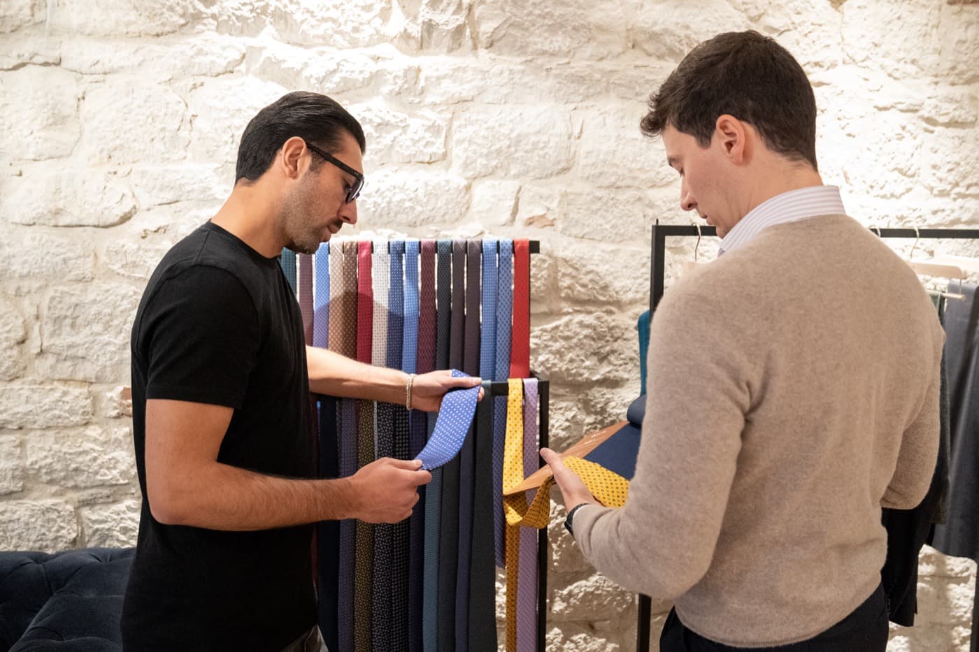 A retailer and a customer choosing cloth and neckwear from a rail during an in-store appointment